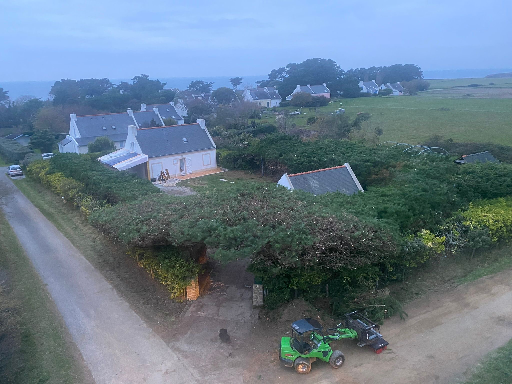 Après intervention : haie taillée et dégagée avec vue ouverte sur la campagne et les maisons environnantes, à Belle-Île-en-Mer